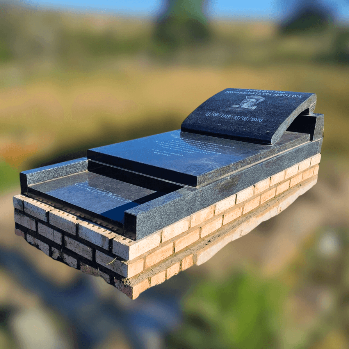 DEX 26 black granite tombstone on a brick base