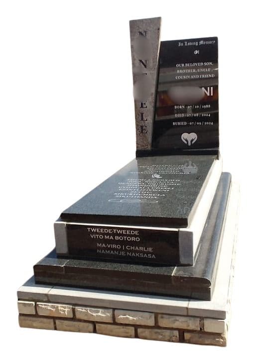 MAX V tombstone: twin upright panels with a tall cover, on a stepped base edged in brick